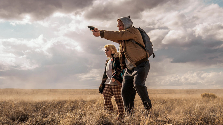 Polly and Nate taking aim in a field in "She Rides Shotgun" (2025)