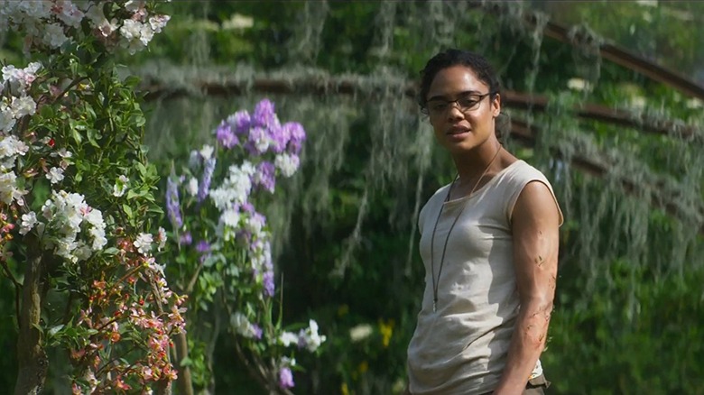 Josie Radek stands close to flowers growing in humanoid patterns in Annihilation