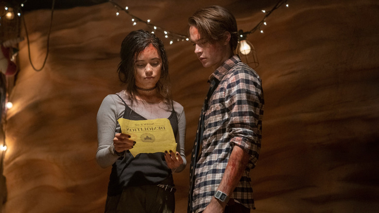 Zoe and Cole looking at a notice in The Babysitter: Killer Queen