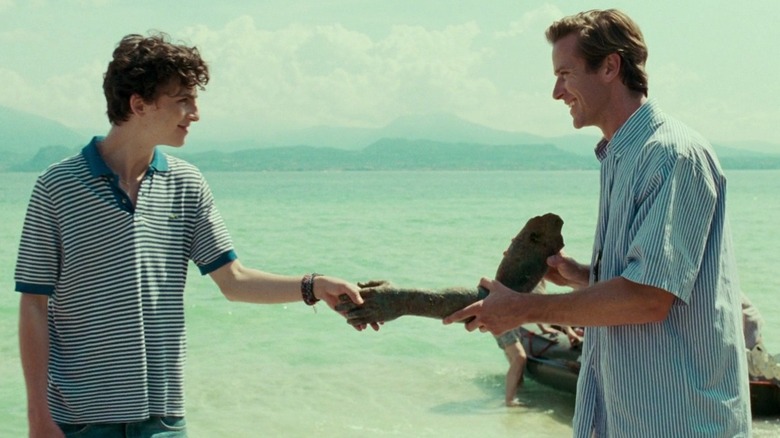 Oliver shaking hands with Elio via ancient remains as they stand in front of the Mediterranean Sea