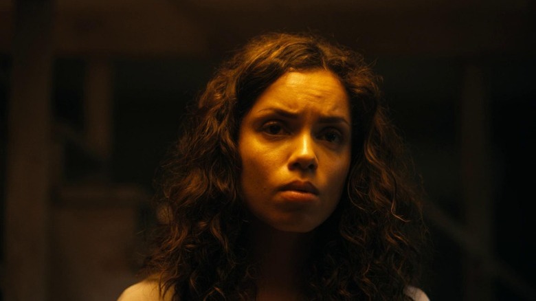 Tess standing in the dark and furrowing her brows in Barbarian