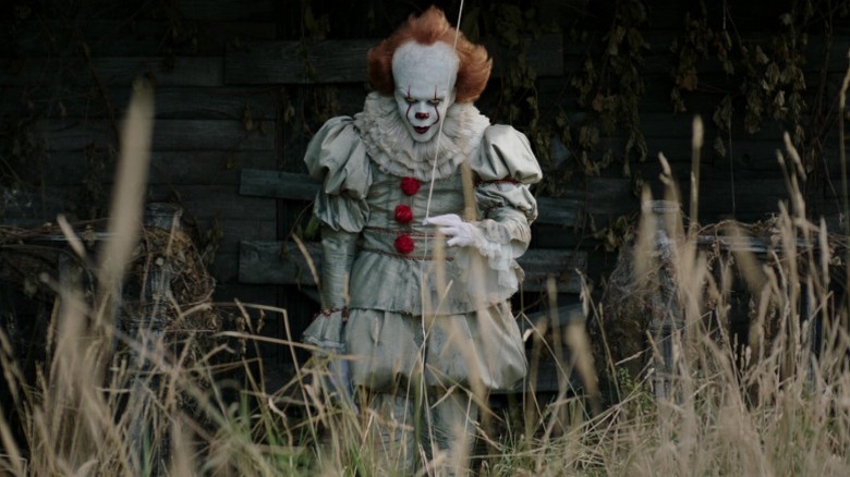Pennywise the Clown holding a balloon and smiling menacingly in It