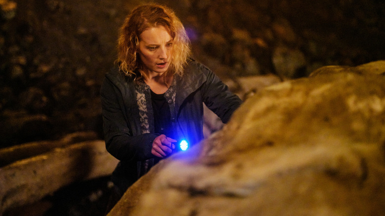 Nora points a flashlight at a rock in "Troll" (2022)