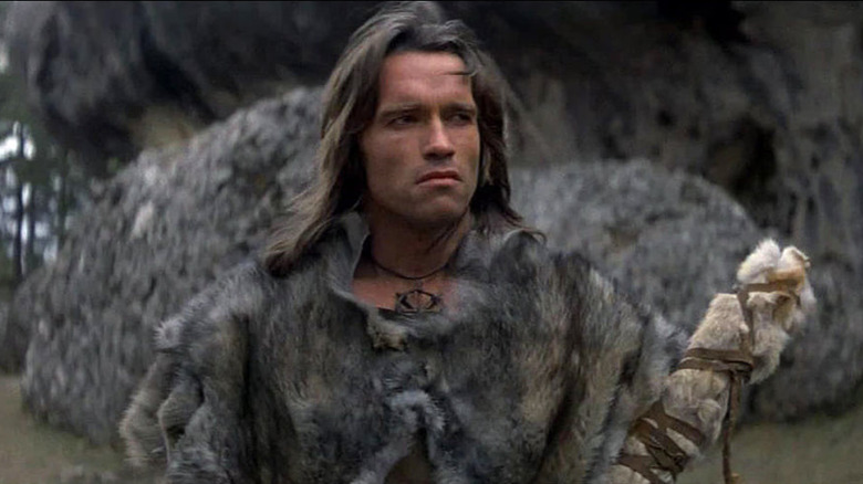 Conan stands in front of a cave in Conan the Barbarian