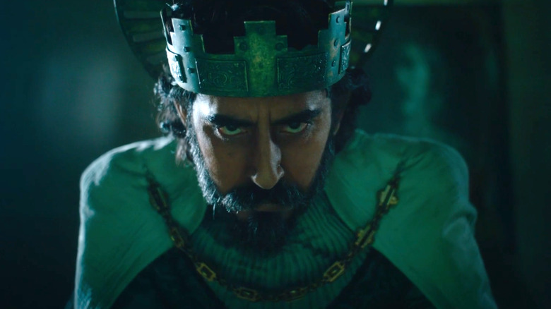 A crowned Gawain peers into the camera in The Green Knight
