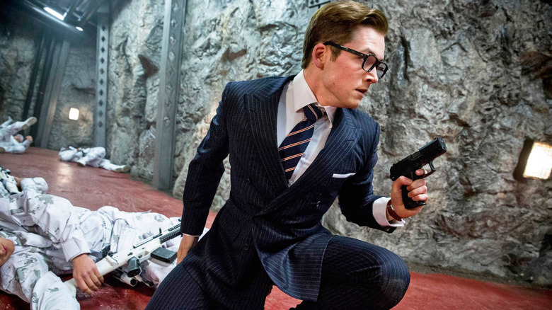 Eggsy squats and holds a gun in "Kingsman: The Secret Service" (2014)
