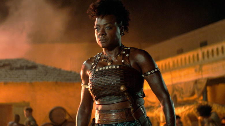 Nanisca stands among burning buildings in "The Woman King" (2022)