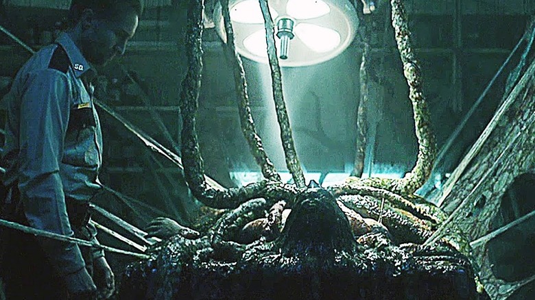 A security guard looks down at a man turning into a tentacled monster in "The Void" (2016)