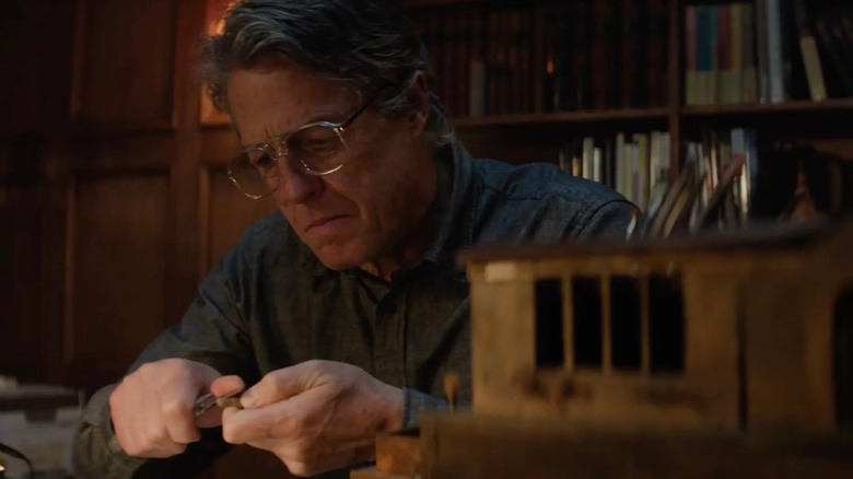 Mr. Reed whittling something next to a small model home in Heretic