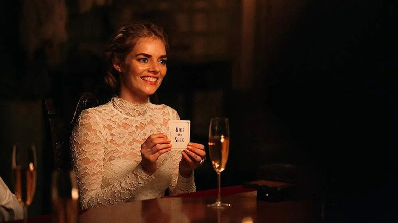 Grace sitting at the table in her wedding dress with a Hide or Seek playing card in Ready or Not