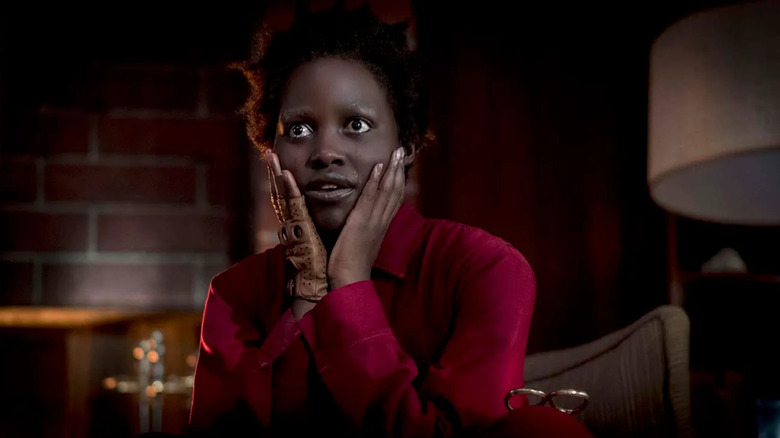 Red with her hands on her face in her jumpsuit in Us