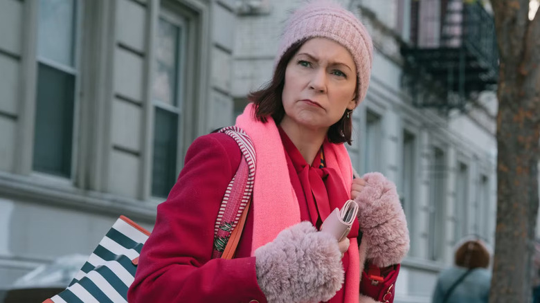 Elsbeth in a pink coat and hat on the street frowning on Elsbeth