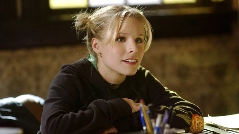 Veronica with her hair in space buns sitting at the desk in her dad's office on Veronica Mars