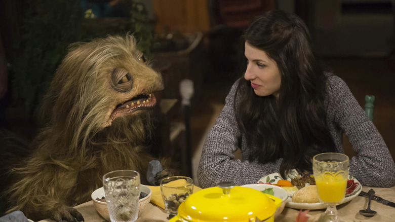 Annie sitting with one of the creatures at a table in "Turkey Hollow"
