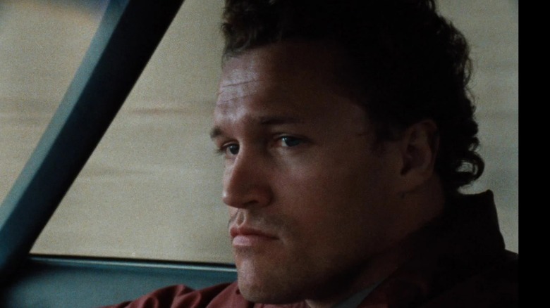 Henry sitting in the front seat of a car in "Henry: Portrait of a Serial Killer"