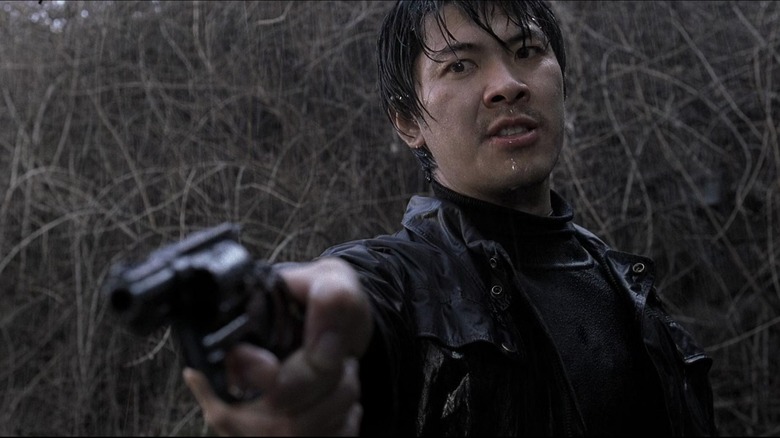 Detective Seo Tae-yoon soaking wet and pointing a gun in "Memories of Murder"