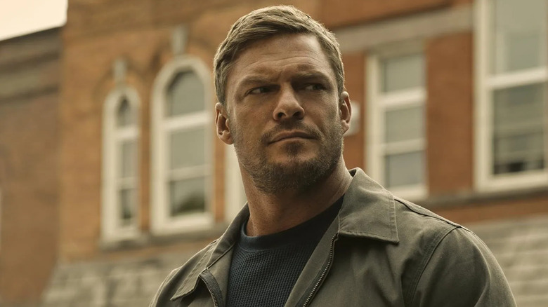 Reacher looks off to his side suspiciously in Reacher