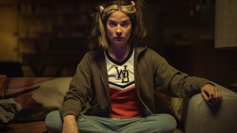 Joan sitting cross-legged on a couch on 