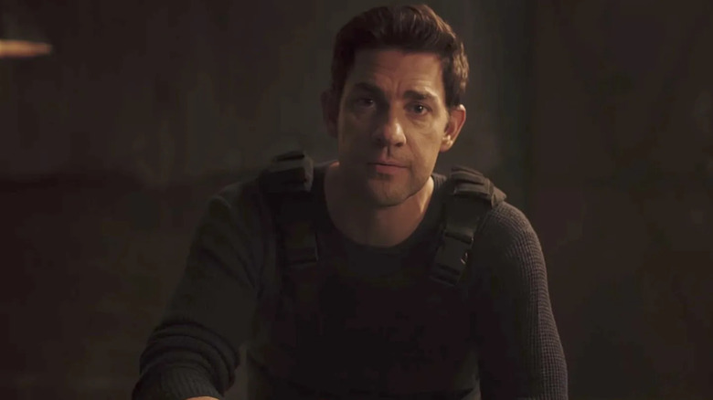 Jack sits at a table and looks at the camera in Jack Ryan