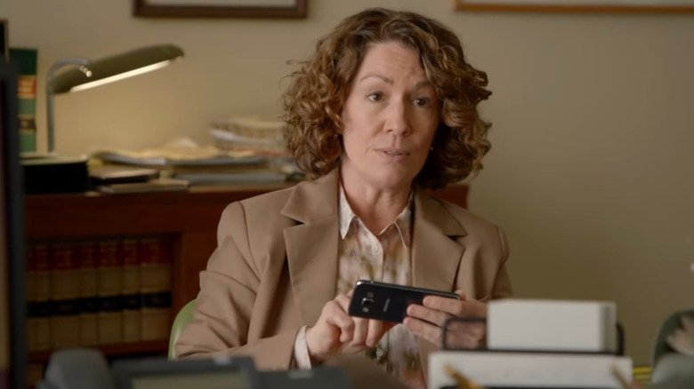 Fisk taps on her cell phone sitting at a desk in Fisk