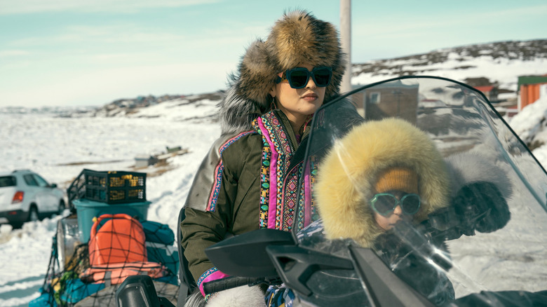 Siaja and her daughter ride on a snowmobile in North of North