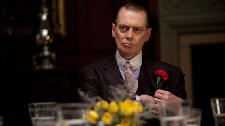 Nucky sits at dinner and affixes a rose to his lapel