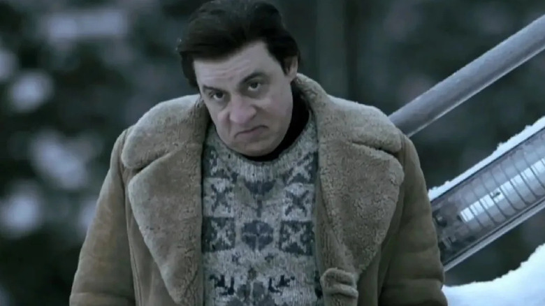 Frank tilts his head and sneers, standing in the snow