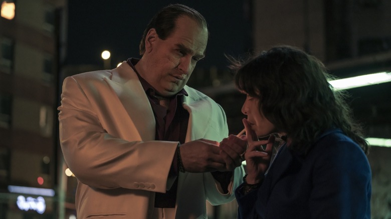 Oz looks down at Sofia and lights her cigarette