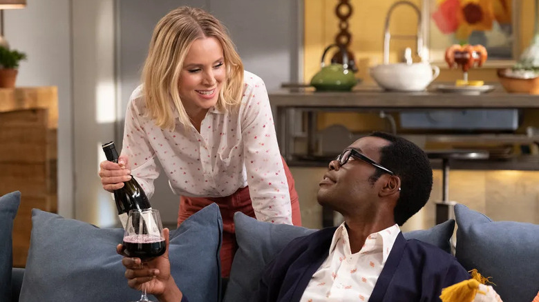Eleanor pouring wine for Chidi on the couch on The Good Place