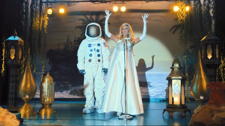 Maxine presenting with a man in a space suit in "Palm Royale" (2024-present)