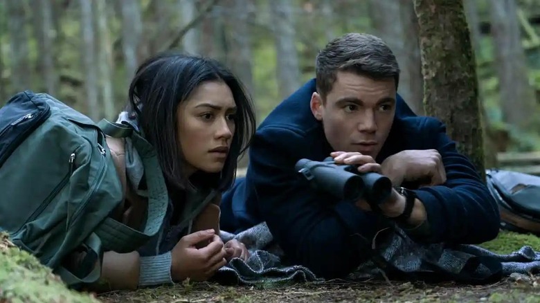 Peter and Rose use binoculars in the woods in The Night Agent