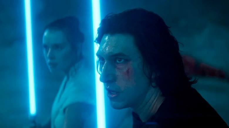 Ben Solo, wearing black, and Rey, in white, each wield blue lightsabers as they stand prepared to battle in "The Rise of Skywalker"