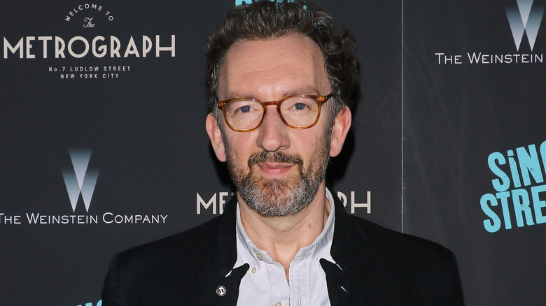 John Carney posing for photographers in a black jacket