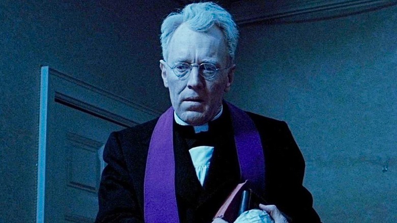 Father Merrin, in purple stole, looks down in The Exorcist (1973)