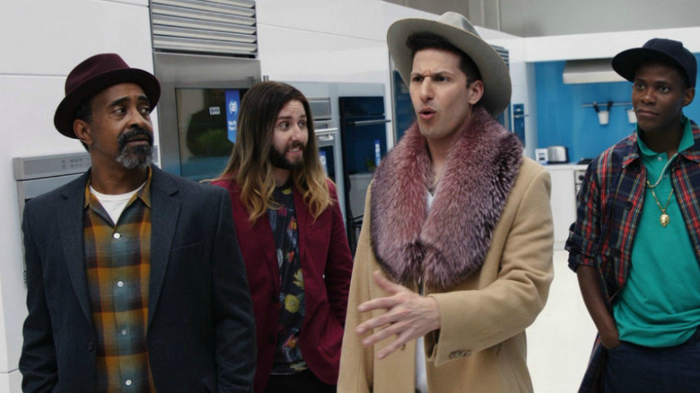 Andy Samberg and his entourage in a hallway