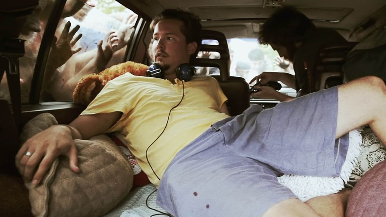 Mickey and Ben sitting in a car that's surrounded by zombies in "The Battery."