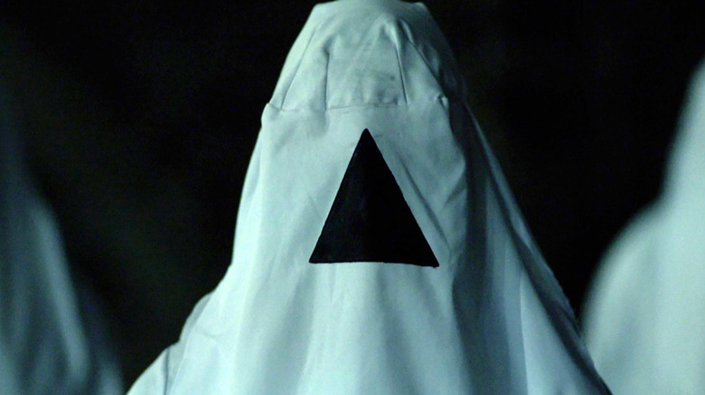A person wearing a white hood with a black triangle in "The Void."