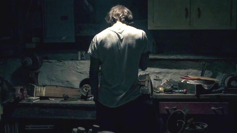 Wyatt standing in front of a work bench in "They Look Like People."