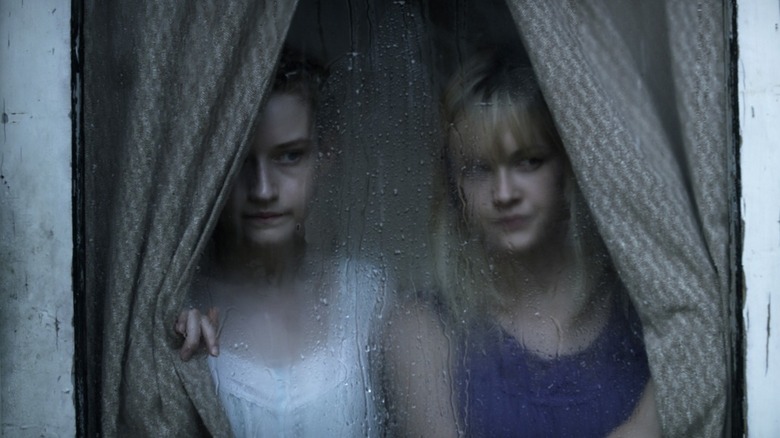Rose and Iris looking out a window in "We Are What We Are."