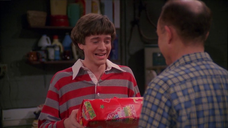 Eric holding a gift in front of Red in "That '70s Show"