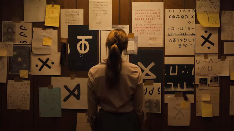 Lee Harker stands before a wall of ciphers in "Longlegs" (2024)