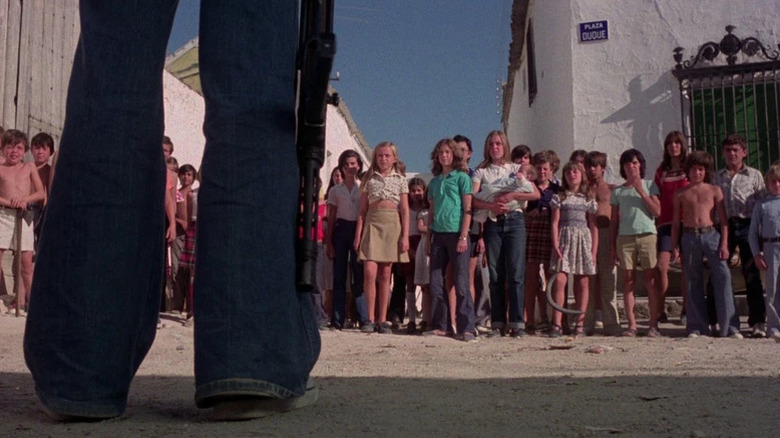 Tom, holding a gun, stands before the island's children in "Who Can Kill a Child?" (1976)