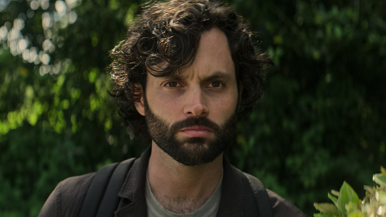 Joe with a beard standing near some trees in "You"