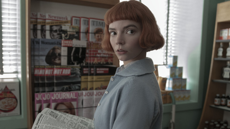 Beth holding a newspaper in "The Queen's Gambit."
