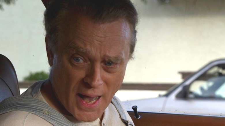 Unsub Adam Rain talking to someone in the front seat of his car