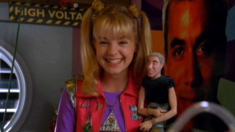 Zenon Kar holds a Proto Zoa doll while grinning in Zenon: Girl of the 21st Century