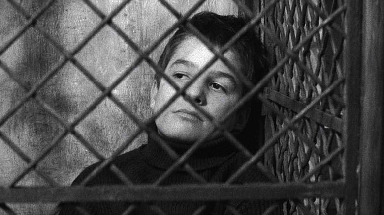 Antoine Doinel sitting behind a fence in "The 400 Blows"