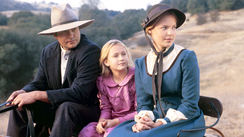 Marty, Clark, and Missy sit on their wagon and look into the distance.
