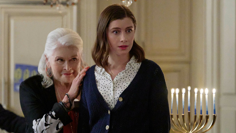 Rosie holds Rachel by the shoulder, who seems surprised at something off-screen.