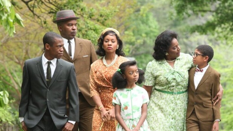 The Watson Family in dress clothes walk through a wooded path.
